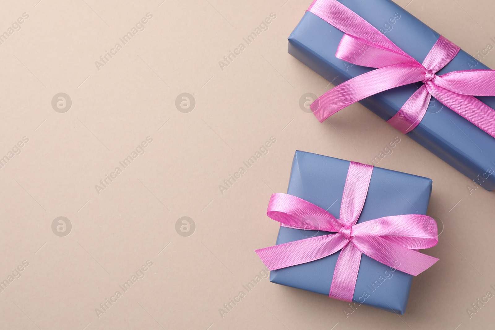 Photo of Gift boxes with pink bows on beige background, top view. Space for text