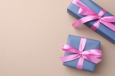 Photo of Gift boxes with pink bows on beige background, top view. Space for text