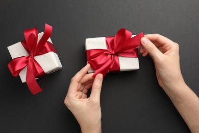 Woman opening gift box on black background, top view