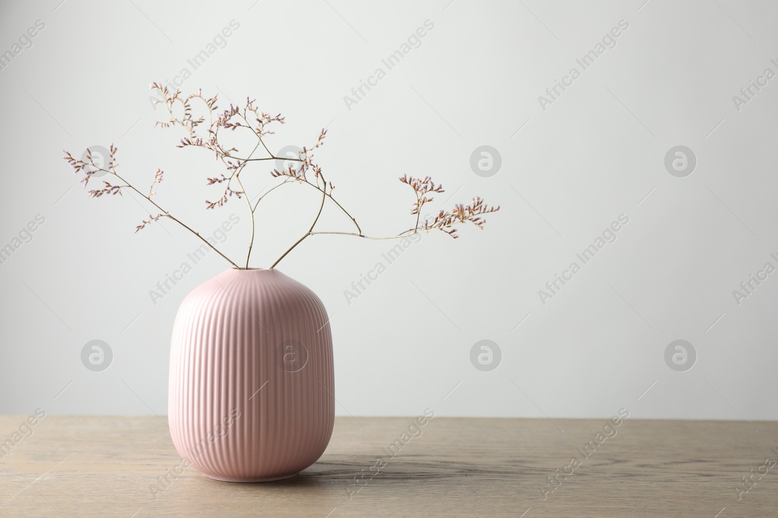 Photo of Stylish vase with beautiful branches on wooden table, space for text