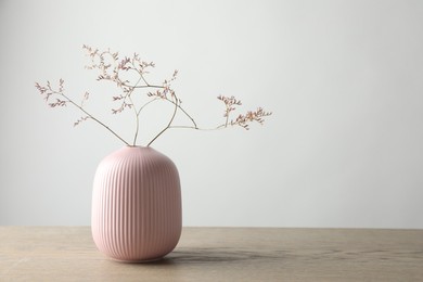 Stylish vase with beautiful branches on wooden table, space for text