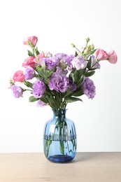 Vase with beautiful eustoma flowers on wooden table