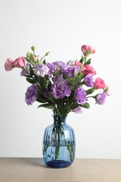 Vase with beautiful eustoma flowers on wooden table