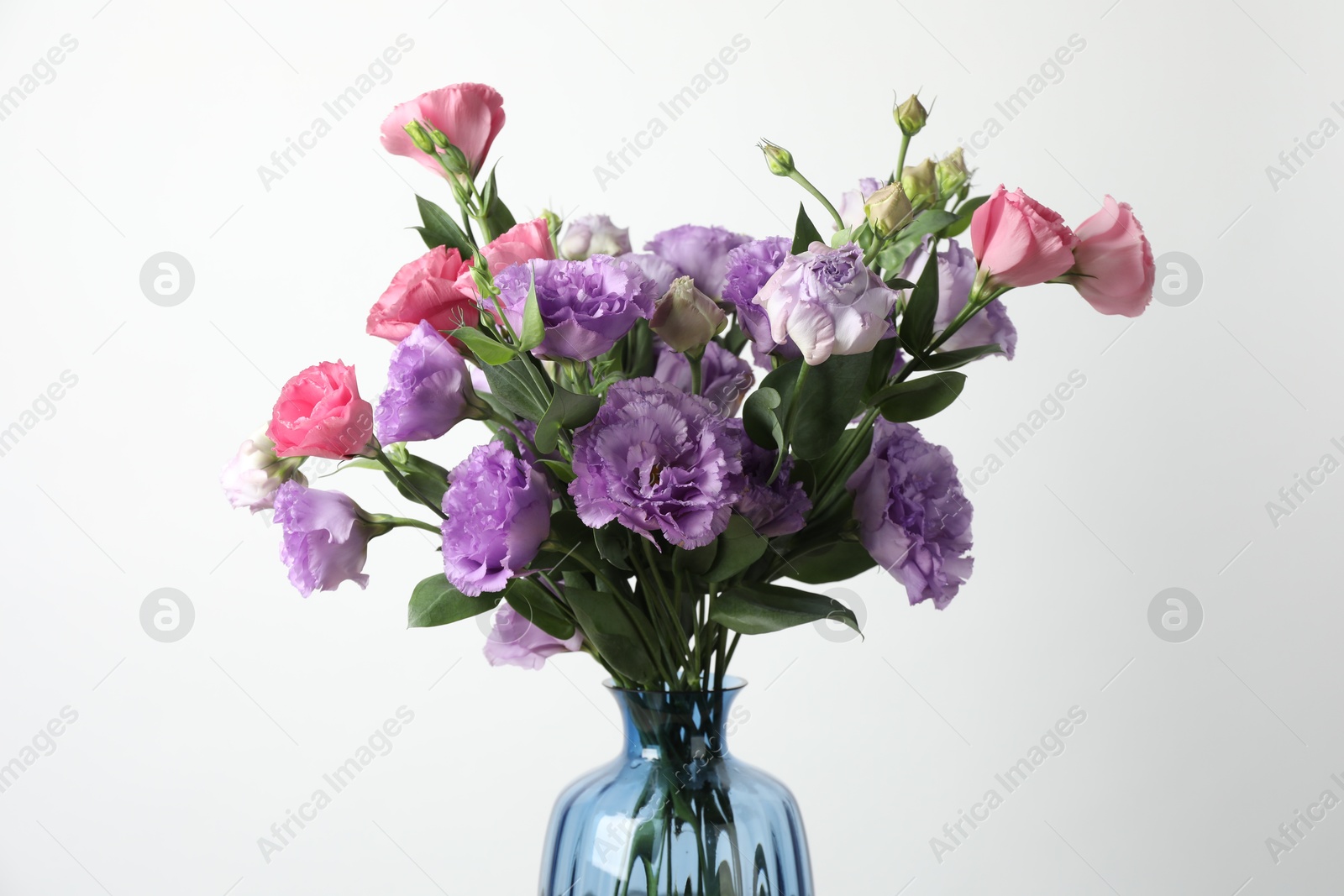 Photo of Vase with beautiful eustoma flowers on light background