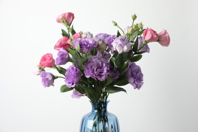 Photo of Vase with beautiful eustoma flowers on light background