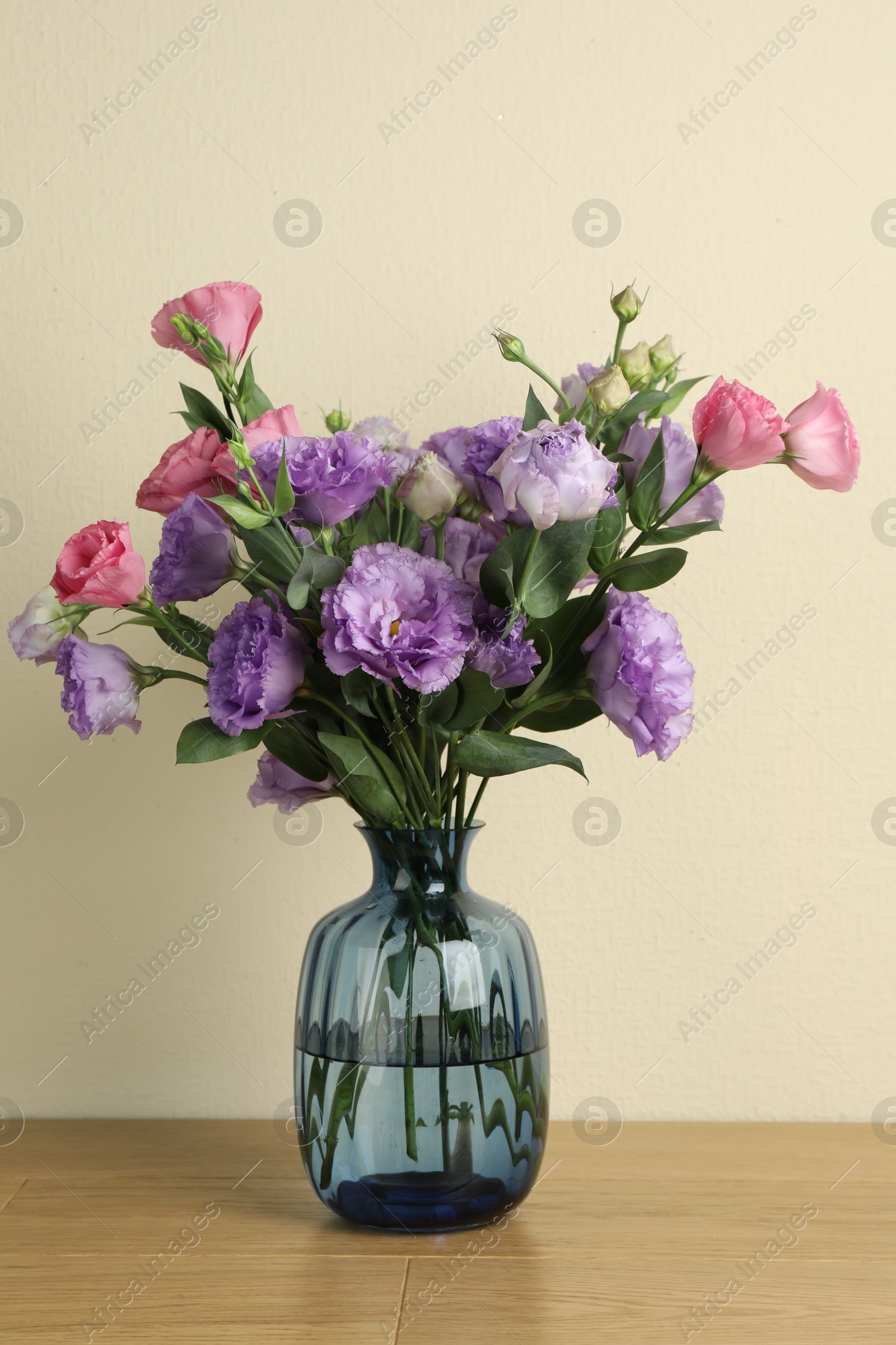 Photo of Vase with beautiful eustoma flowers on wooden table