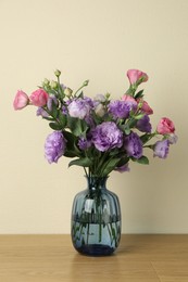 Vase with beautiful eustoma flowers on wooden table