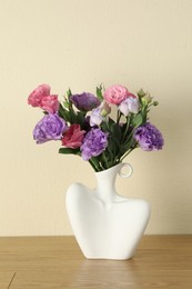 Photo of Vase with beautiful eustoma flowers on wooden table