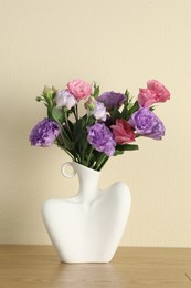 Photo of Vase with beautiful eustoma flowers on wooden table