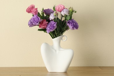 Photo of Vase with beautiful eustoma flowers on wooden table