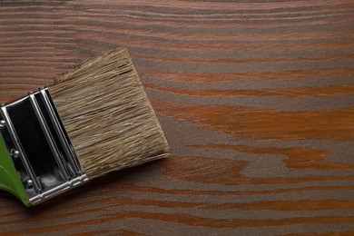 Photo of Applying walnut wood stain. Brush on wooden surface, top view. Space for text