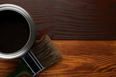 Photo of Applying walnut wood stain. Brush and can on wooden surface, flat lay. Space for text