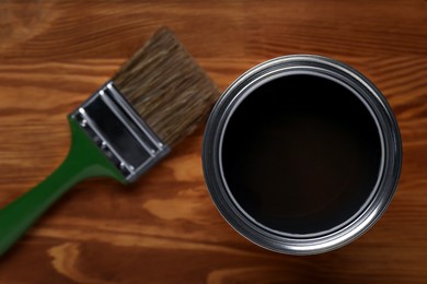 Photo of Applying walnut wood stain. Brush and can on wooden surface, flat lay