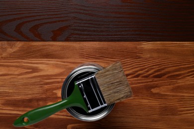 Applying walnut wood stain. Brush and can on wooden surface, flat lay