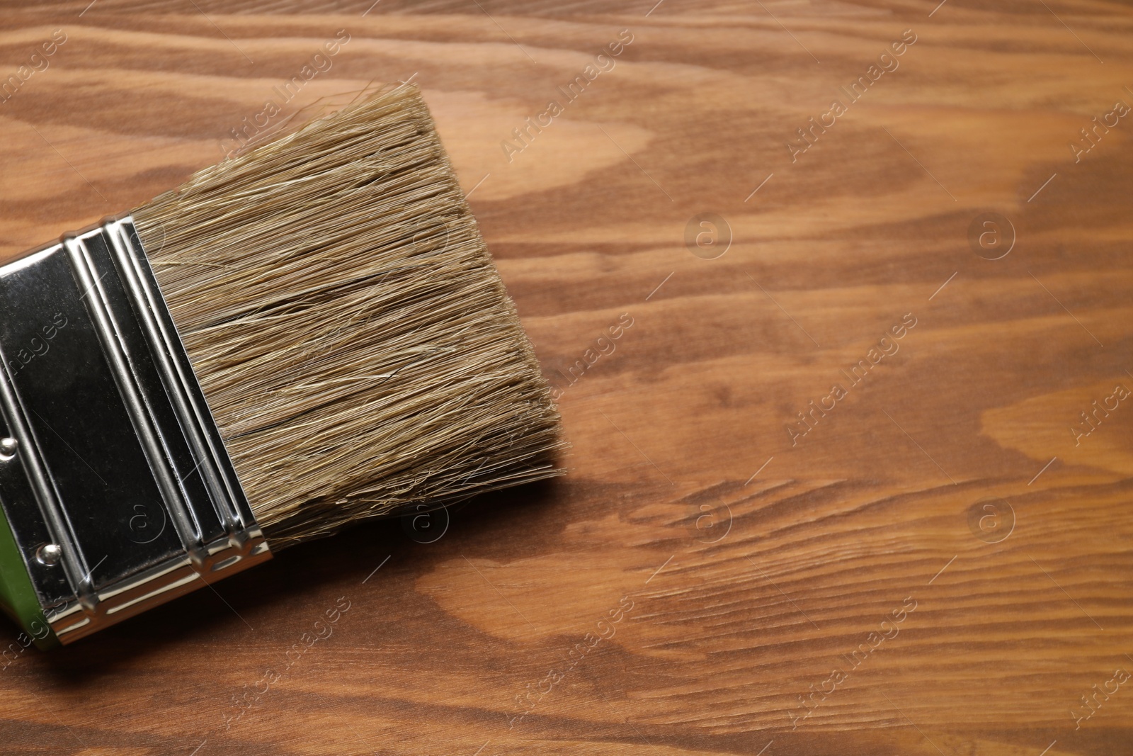 Photo of Applying walnut wood stain. Brush on wooden surface, top view. Space for text