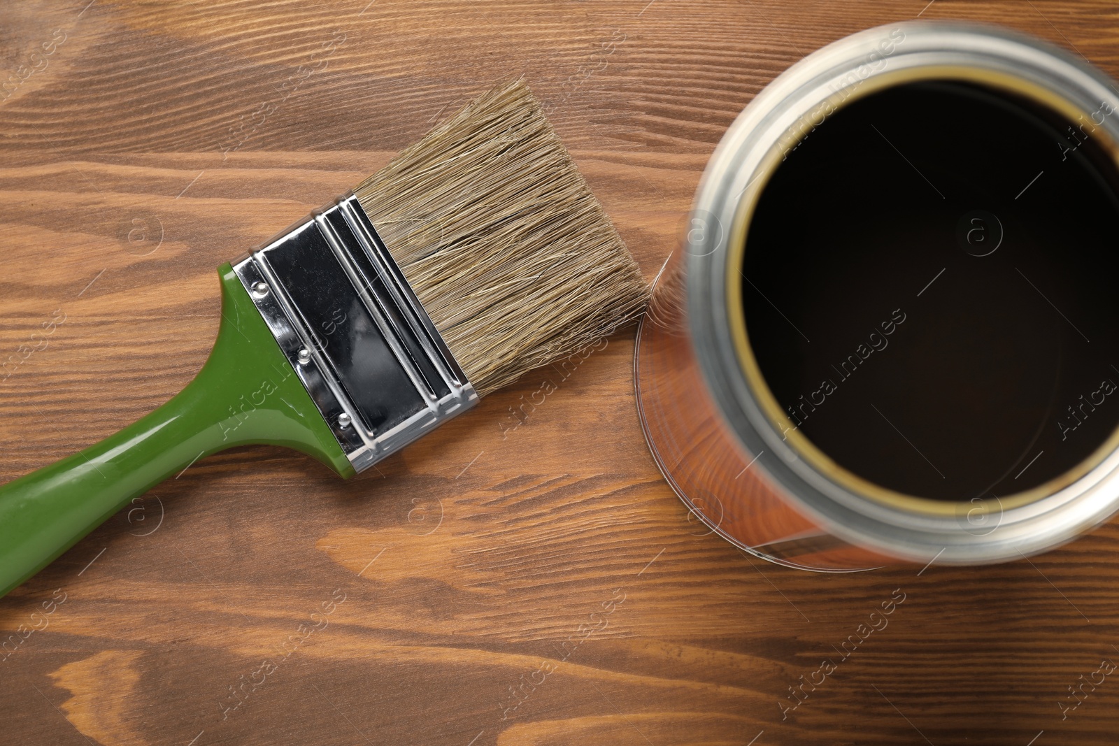 Photo of Applying walnut wood stain. Brush and can on wooden surface, flat lay