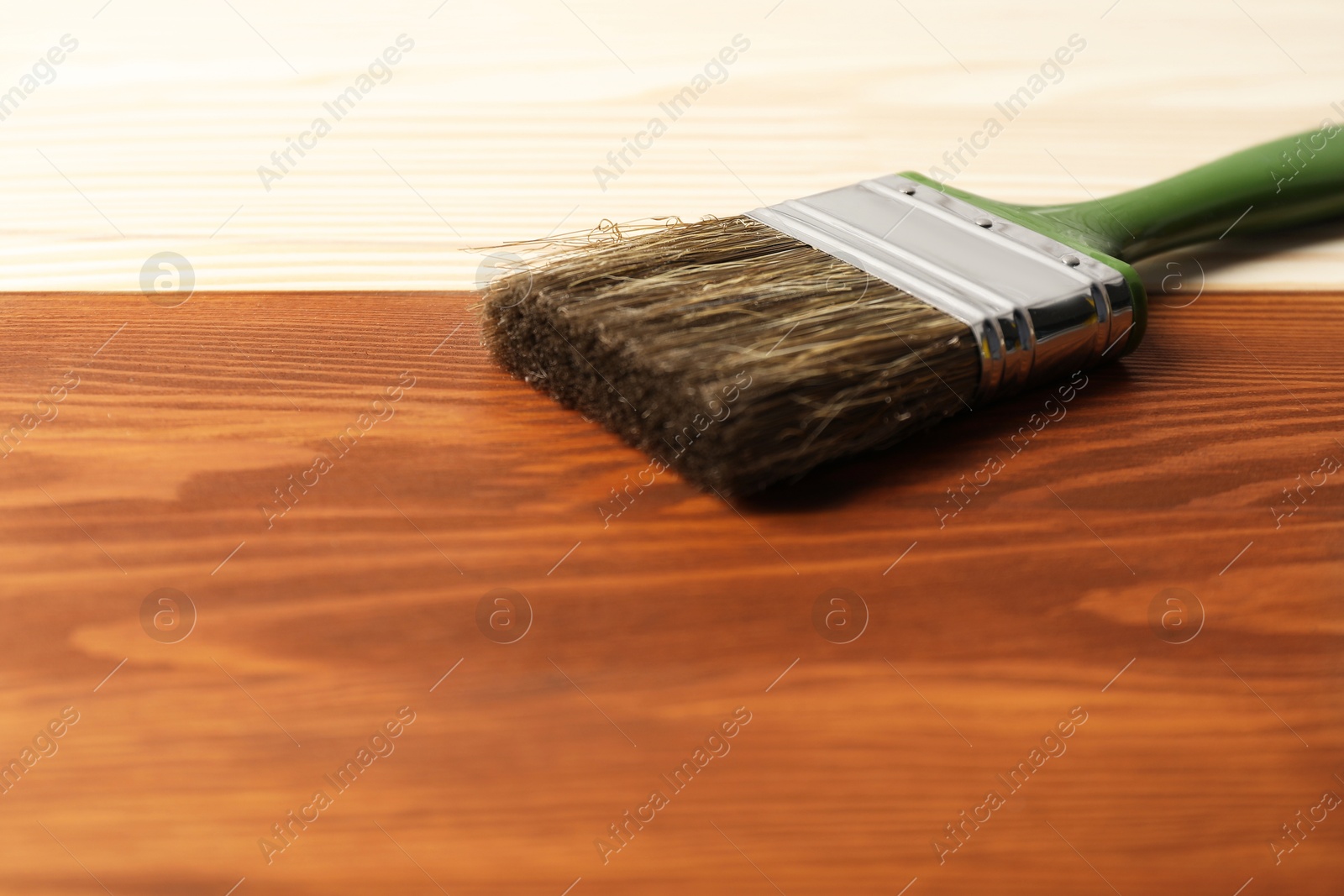 Photo of Applying walnut wood stain. Brush on wooden surface, closeup