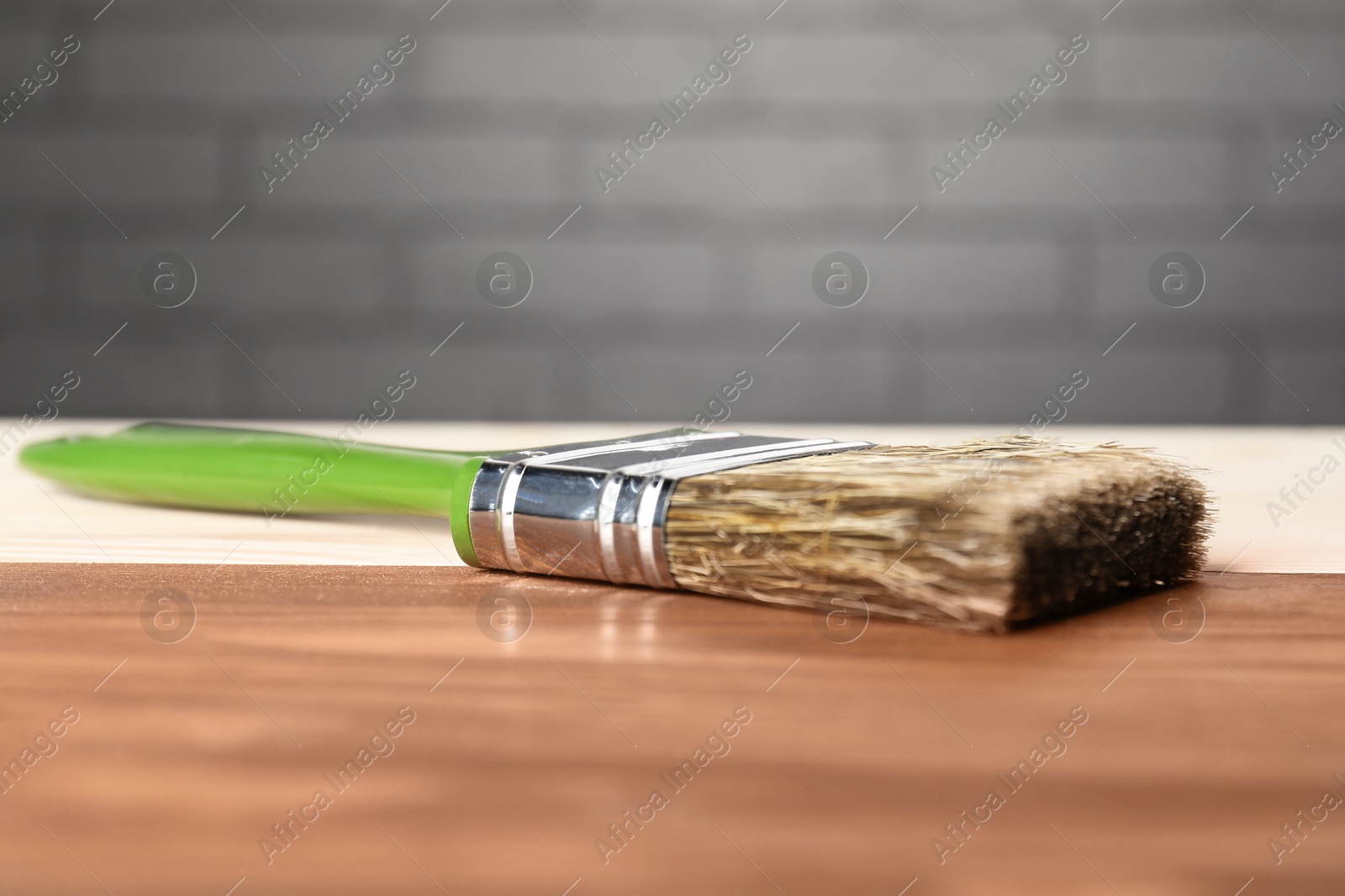 Photo of Applying walnut wood stain. Brush on wooden surface, closeup