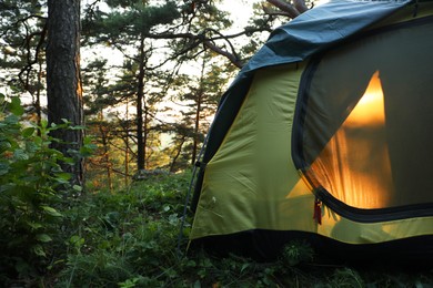 Photo of Modern camping tent in forest at summer, space for text