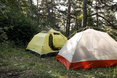 Photo of Modern camping tents in forest on sunny day