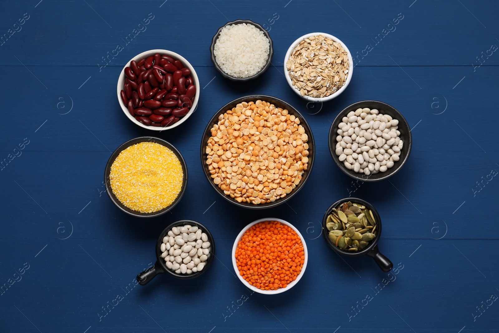 Photo of Different types of cereals, seeds and legumes on blue wooden table, flat lay