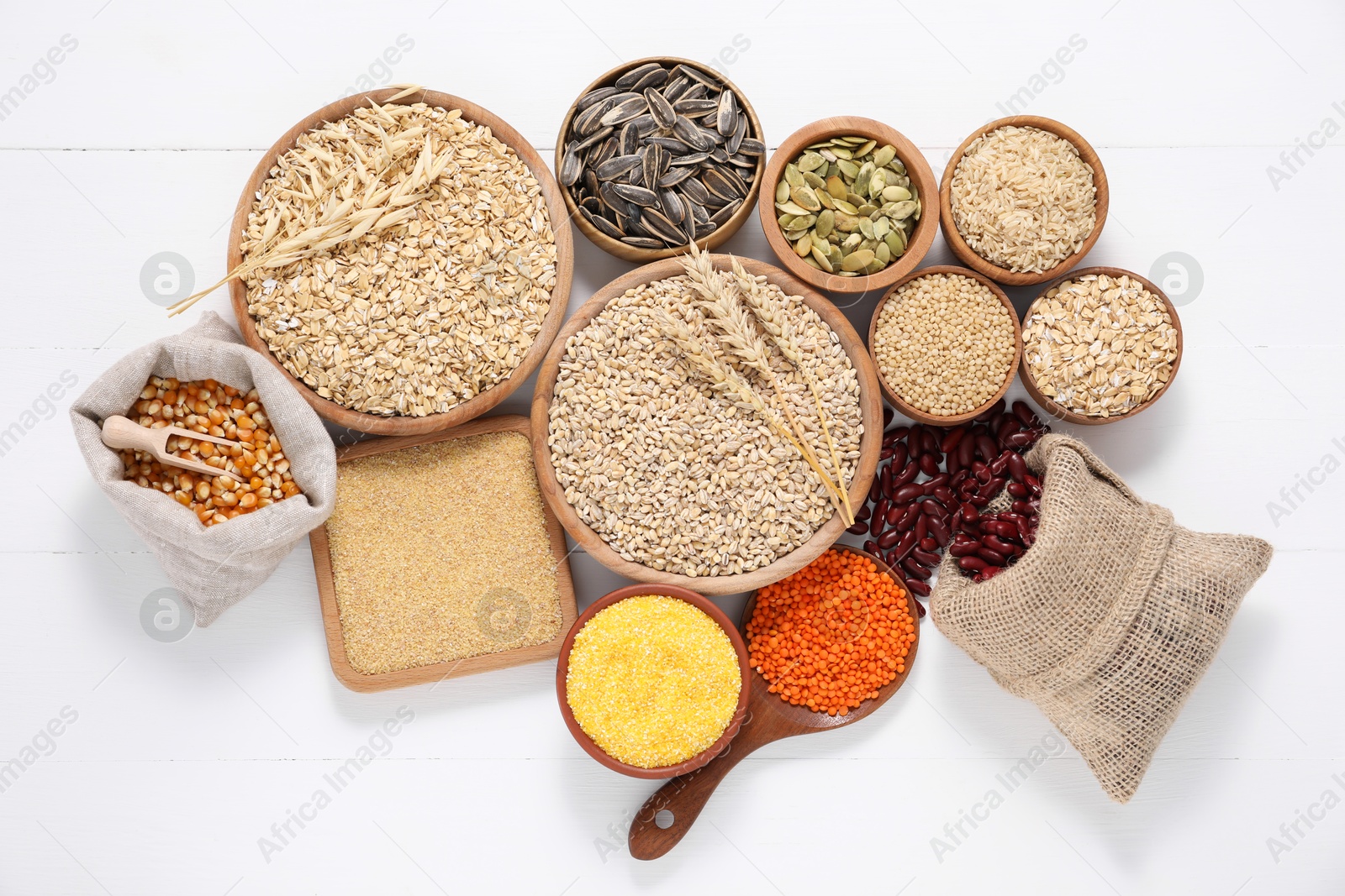 Photo of Different types of cereals, seeds and legumes on white wooden table, flat lay