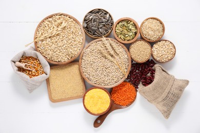 Photo of Different types of cereals, seeds and legumes on white wooden table, flat lay