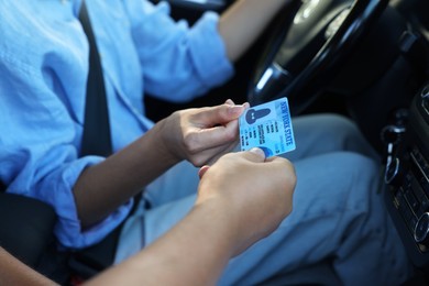 Driving school. Examiner giving driving license to student after exam in car, closeup