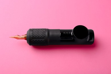 Photo of Professional permanent makeup machine with power supply on pink background