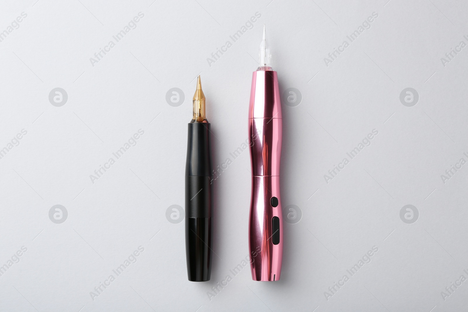 Photo of Professional permanent makeup machines on light grey background, top view