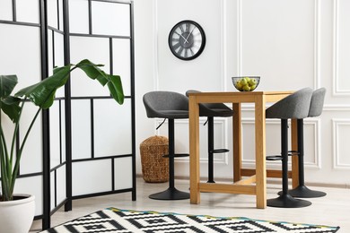 Photo of Bar stools, table, houseplant and folding screen indoors