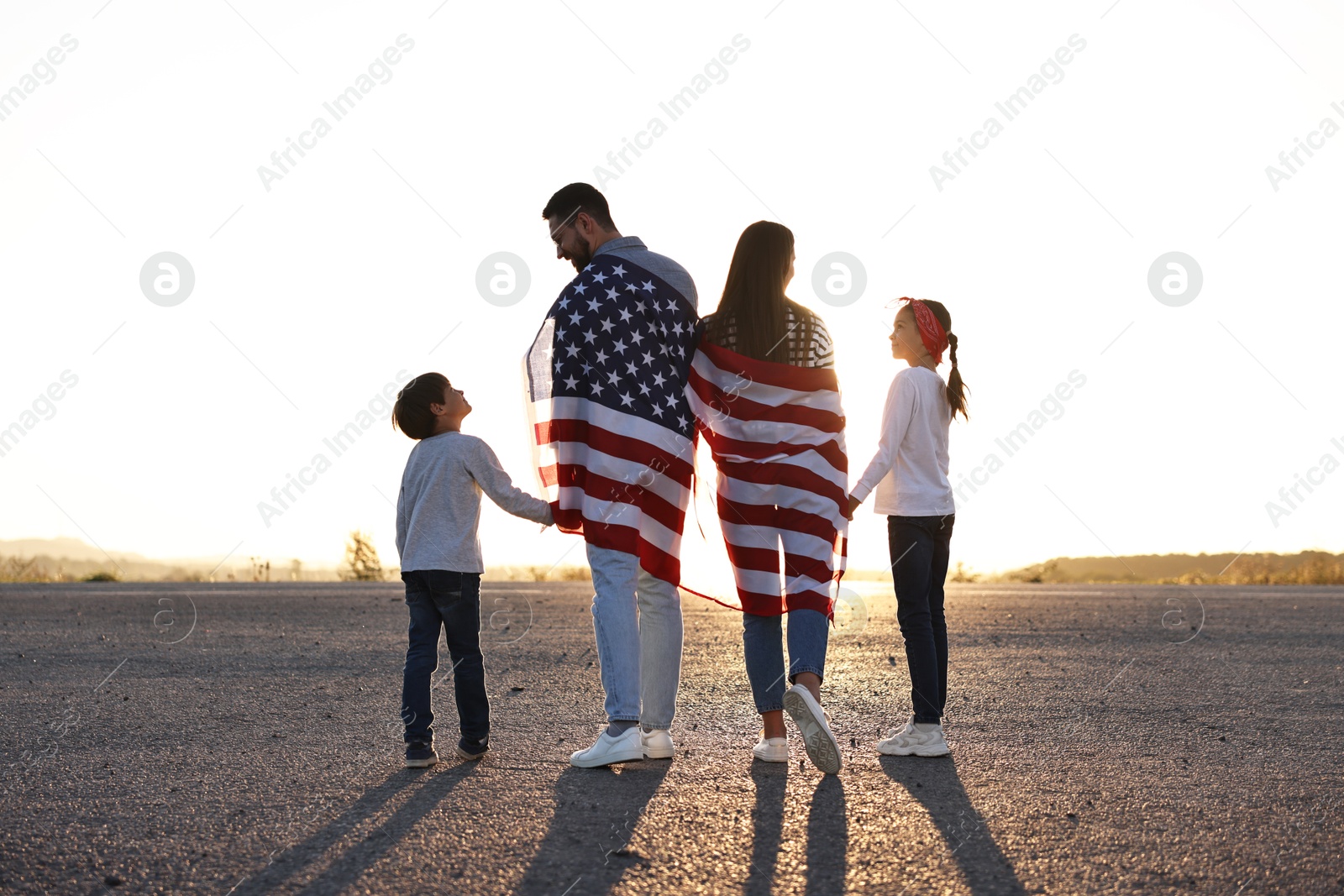 Photo of Family with flag of USA walking outdoors, back view