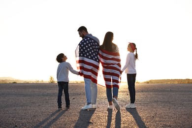 Photo of Family with flag of USA walking outdoors, back view