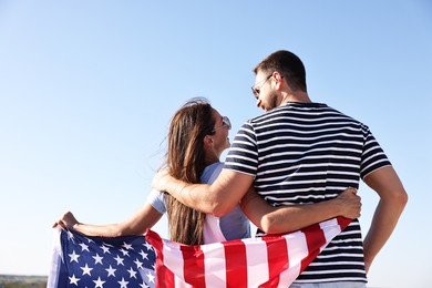 Couple with flag of USA outdoors, back view