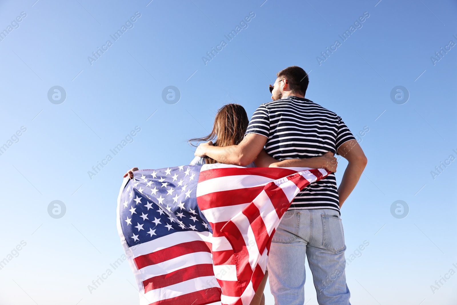 Photo of Couple with flag of USA outdoors, back view