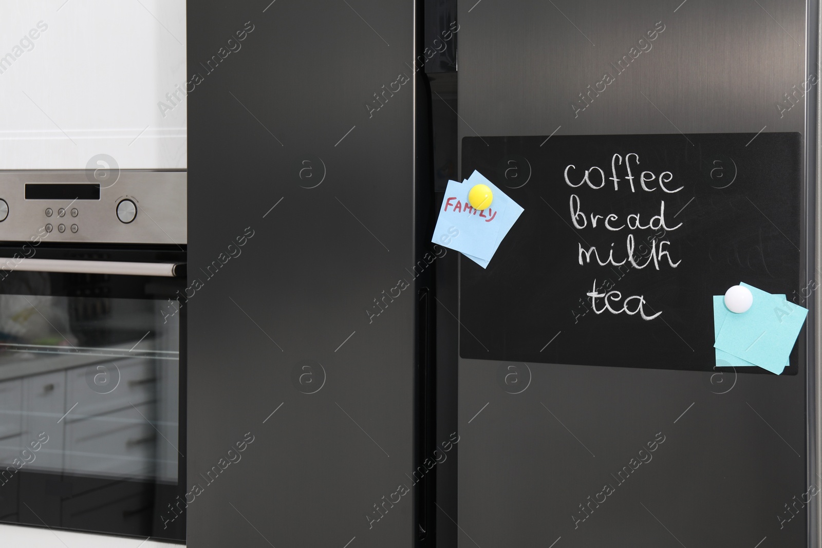 Photo of Magnetic board with shopping list and notes on refrigerator in kitchen