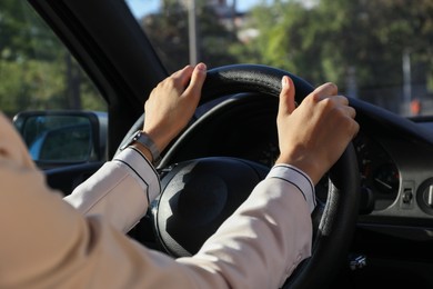 Woman holding steering wheel while driving car, closeup