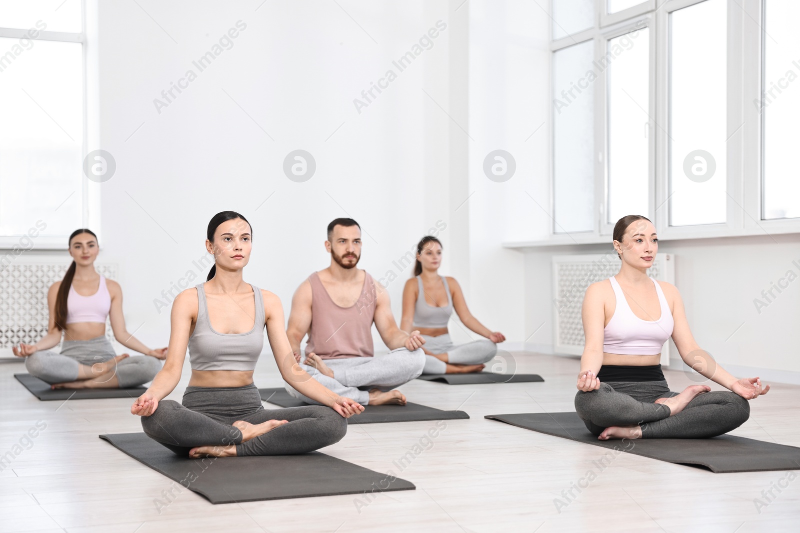 Photo of Group of people meditating on mats in yoga class