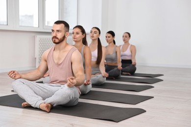 Group of people meditating on mats in yoga class. Space for text