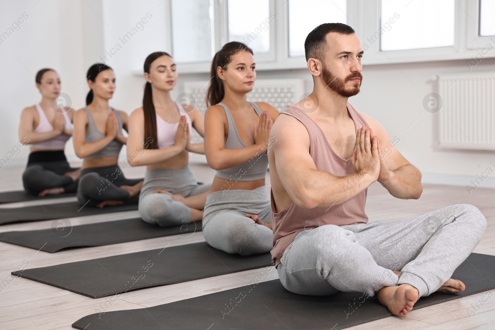 Photo of Group of people meditating on mats in yoga class