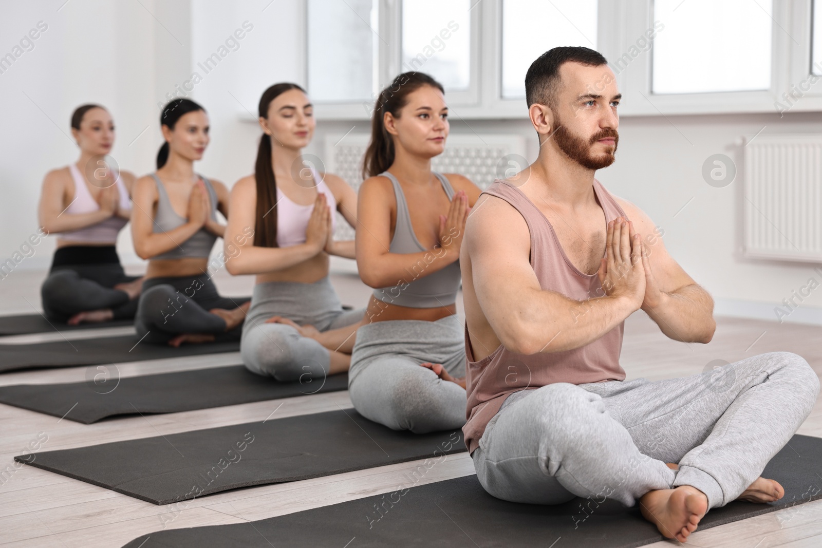 Photo of Group of people meditating on mats in yoga class