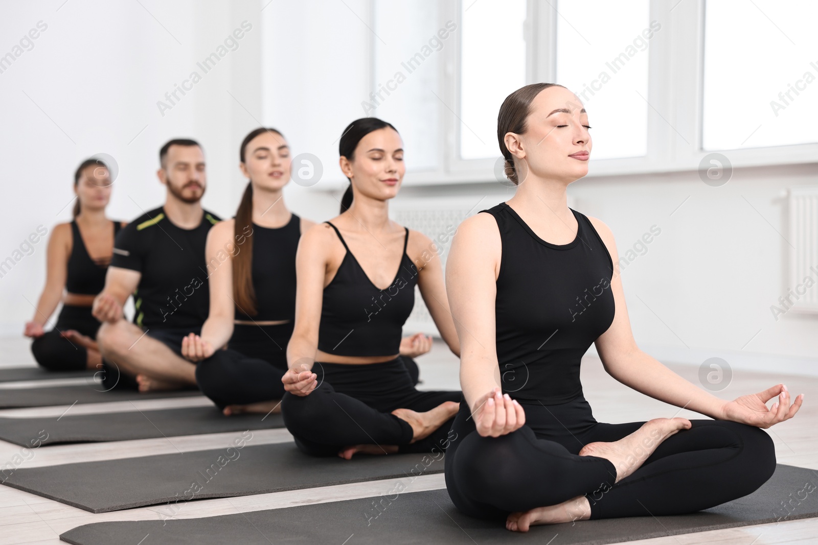 Photo of Group of people meditating on mats in yoga class