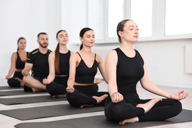 Photo of Group of people meditating on mats in yoga class