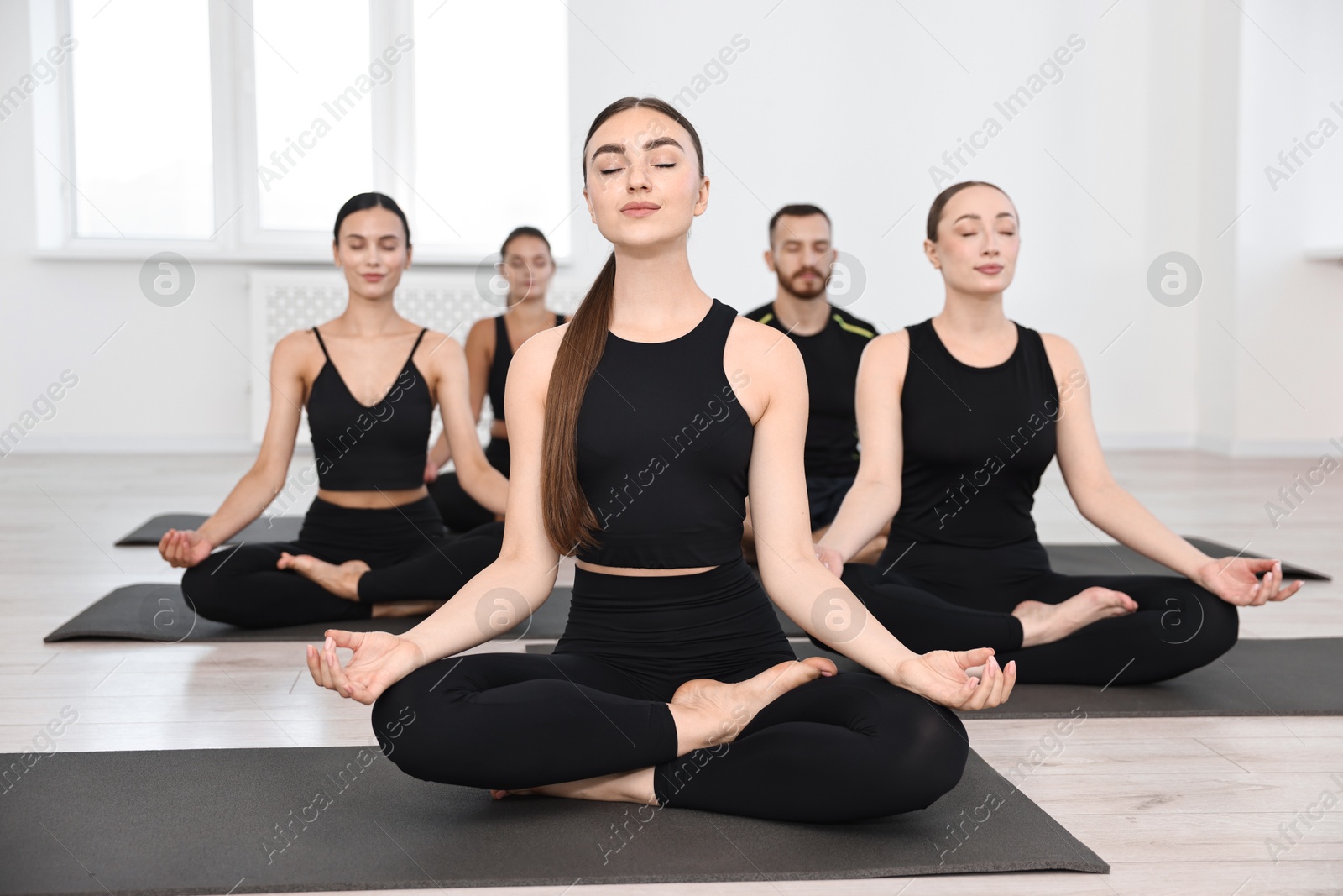 Photo of Group of people meditating on mats in yoga class