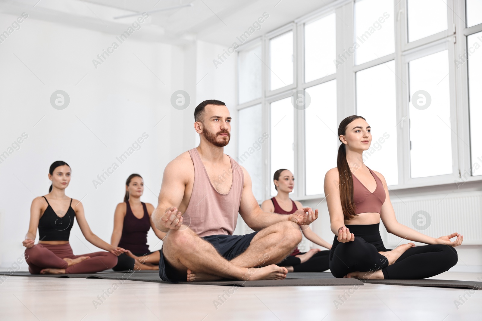 Photo of Group of people meditating on mats in yoga class