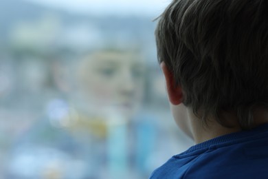 Autism concept. Lonely little boy near window at home, space for text