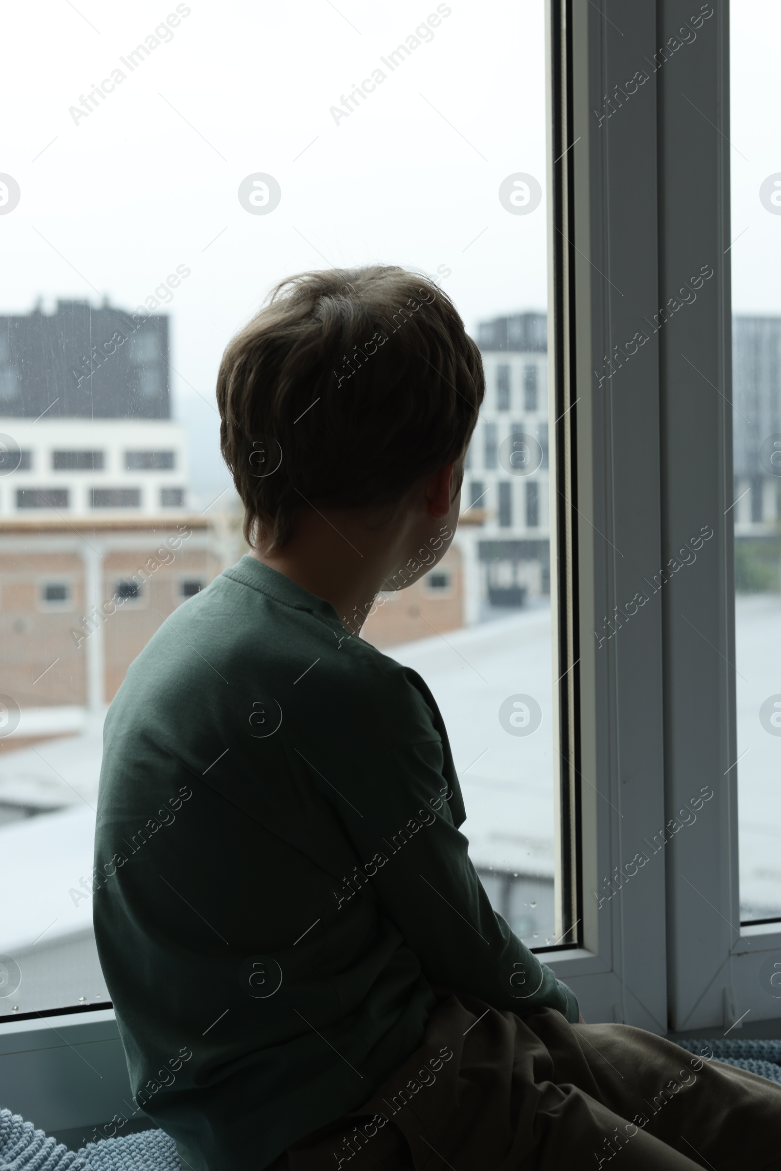 Photo of Autism concept. Lonely little boy near window at home