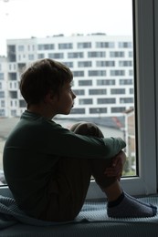 Photo of Autism concept. Lonely little boy near window at home