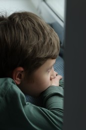 Autism concept. Lonely little boy near window at home