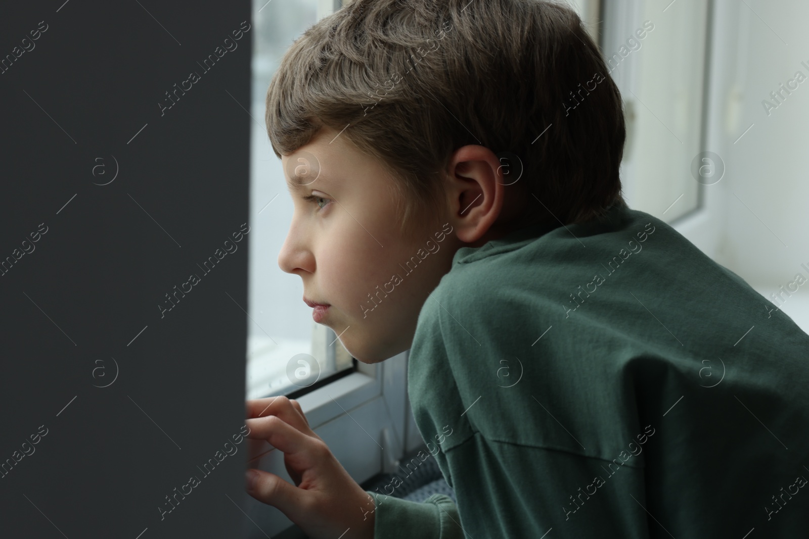 Photo of Autism concept. Lonely little boy near window at home